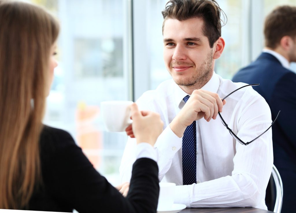 Two professionals having a discussion over coffee, emphasizing collaboration in the screening process