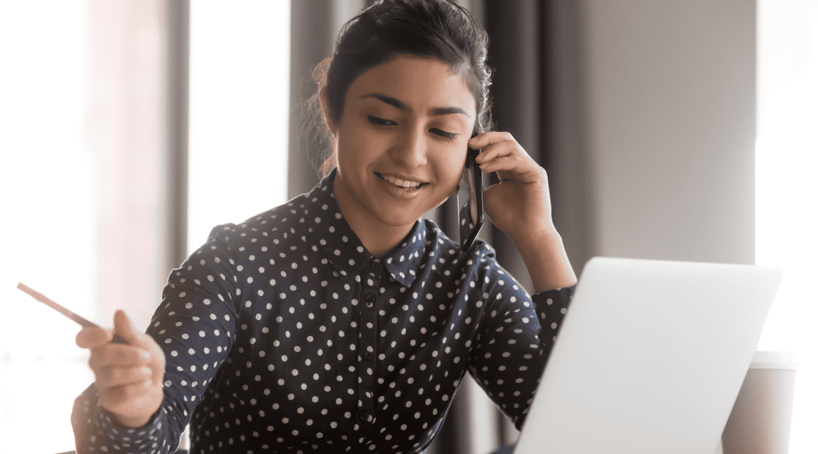 Smiling young woman noting down something during an online video call