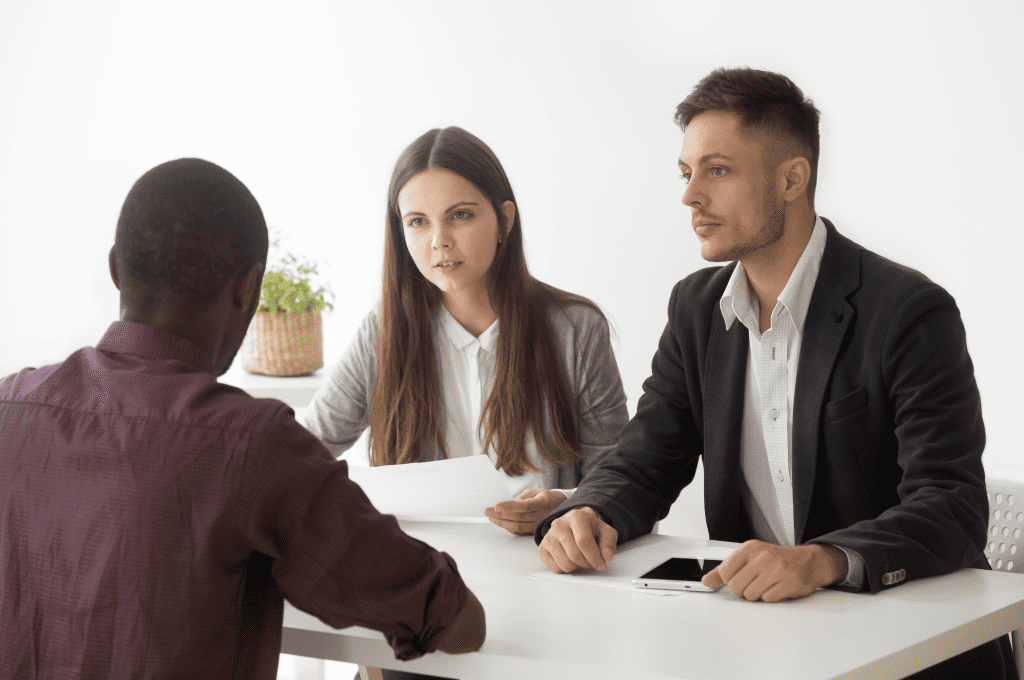 Serious HR managers listen to an African applicant in a job interview