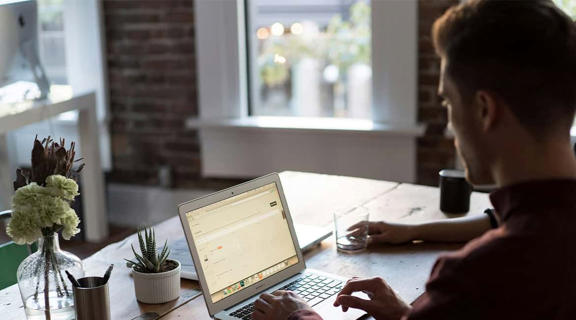 A man sitting at a desk in an office, focused on his laptop, illustrating the use of email automation in HR for efficient recruitment processes.